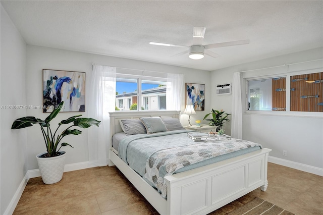 bedroom featuring a wall unit AC, light tile patterned flooring, a ceiling fan, and baseboards