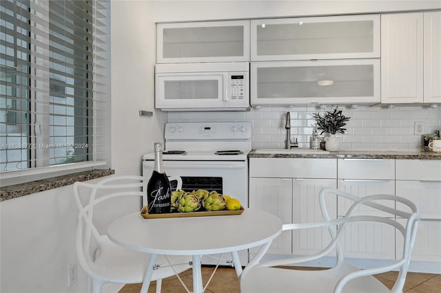 kitchen with white appliances, light tile patterned floors, backsplash, sink, and white cabinets