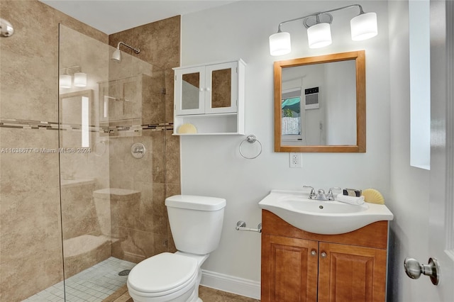 full bath with baseboards, tiled shower, toilet, and vanity