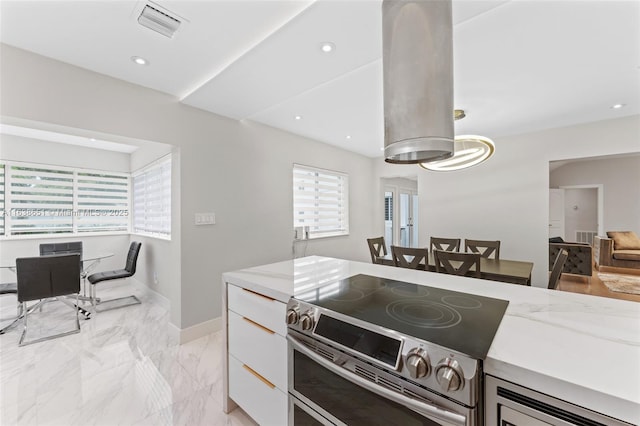 kitchen featuring white cabinetry, visible vents, light stone countertops, and double oven range