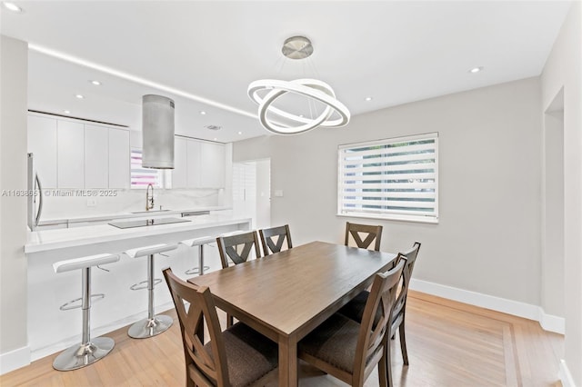 dining space with light wood finished floors, an inviting chandelier, baseboards, and recessed lighting