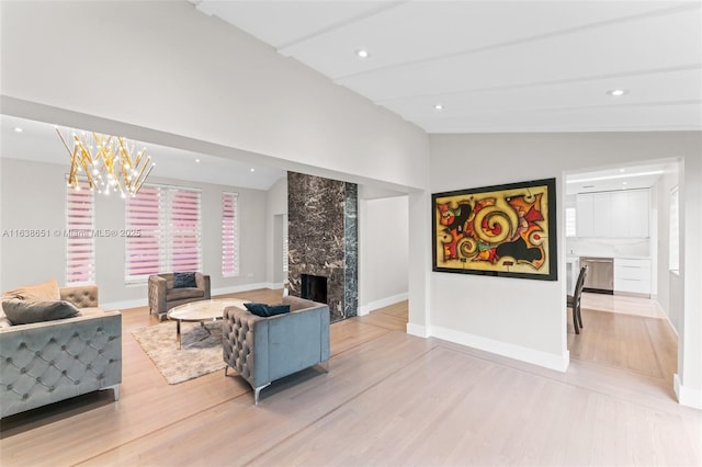 living room featuring a notable chandelier, a premium fireplace, light wood-type flooring, and vaulted ceiling