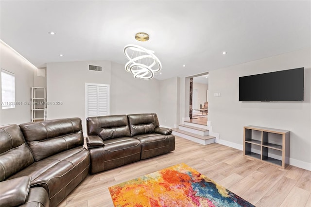 living room with lofted ceiling, an inviting chandelier, and light hardwood / wood-style flooring