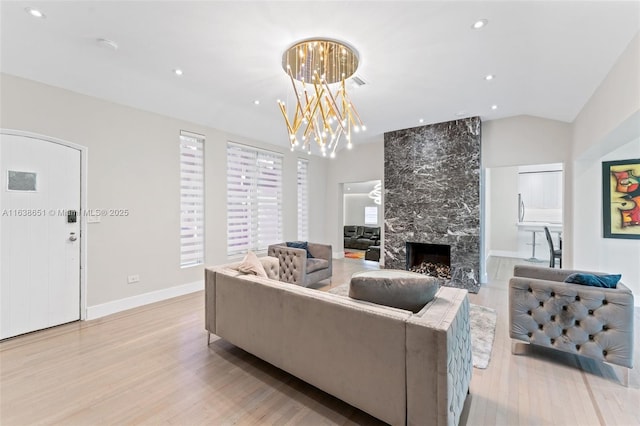 living room featuring recessed lighting, a fireplace, lofted ceiling, and light wood-style flooring