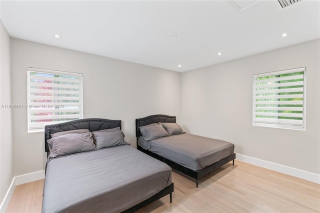 bedroom with light wood-style flooring, baseboards, and multiple windows