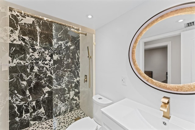 bathroom featuring toilet, a tile shower, and vanity