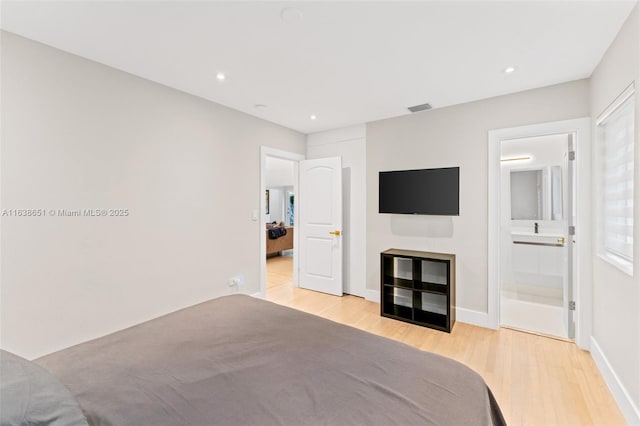 bedroom with connected bathroom and light wood-type flooring