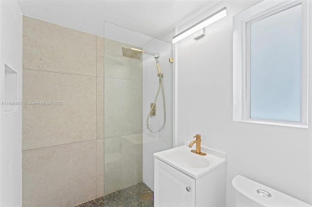 bathroom with a tile shower, vanity, and toilet