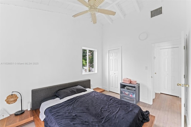 bedroom with beam ceiling, visible vents, a ceiling fan, wood finished floors, and high vaulted ceiling