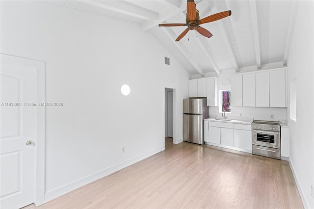 kitchen with stainless steel appliances, light countertops, a ceiling fan, beam ceiling, and light wood-style flooring