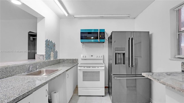 kitchen featuring light tile patterned floors, appliances with stainless steel finishes, sink, and light stone countertops