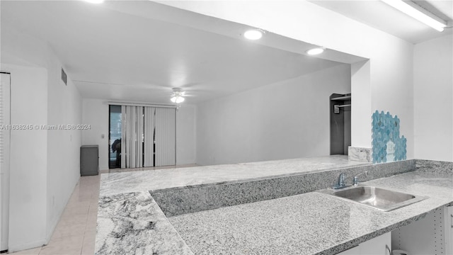 kitchen featuring ceiling fan, sink, light stone counters, and light tile patterned floors