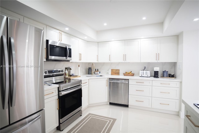 kitchen featuring decorative backsplash, stainless steel appliances, sink, and white cabinetry