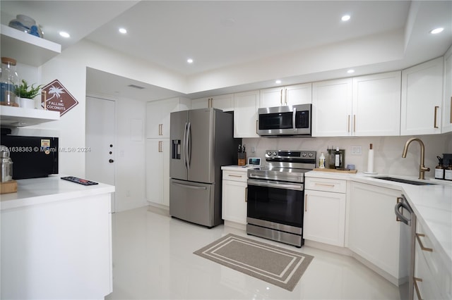 kitchen featuring appliances with stainless steel finishes, white cabinets, tasteful backsplash, and sink