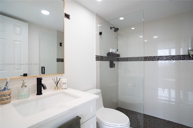 bathroom featuring a shower with shower door, vanity, and toilet