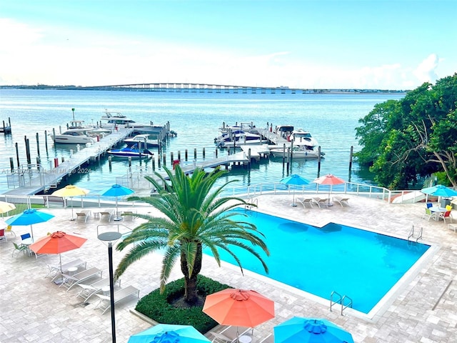 view of swimming pool featuring a patio area, a water view, and a boat dock