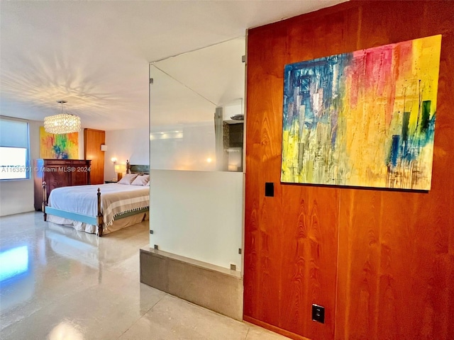 bedroom with concrete flooring, wooden walls, and a notable chandelier