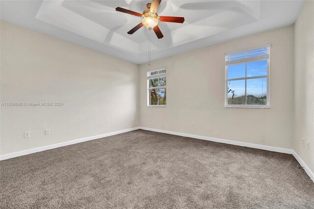 unfurnished room with ceiling fan, carpet floors, and a tray ceiling