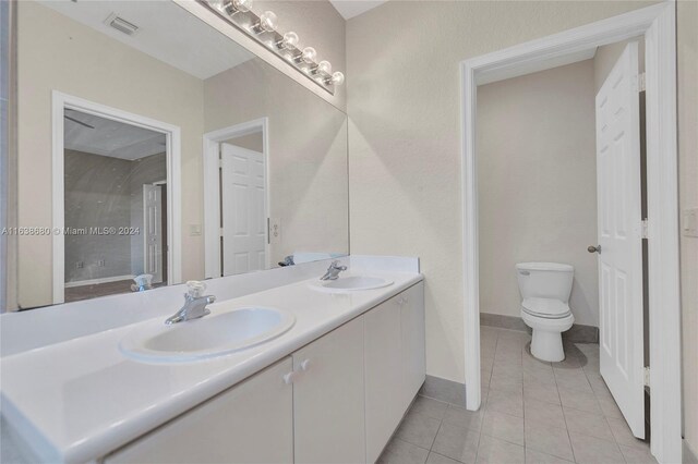 bathroom featuring double sink vanity, toilet, and tile patterned flooring