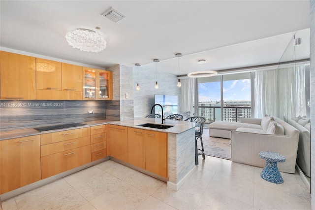 kitchen with visible vents, a peninsula, a sink, glass insert cabinets, and black electric stovetop