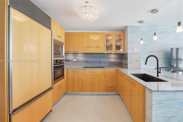 kitchen featuring a sink, light stone counters, a peninsula, glass insert cabinets, and built in appliances