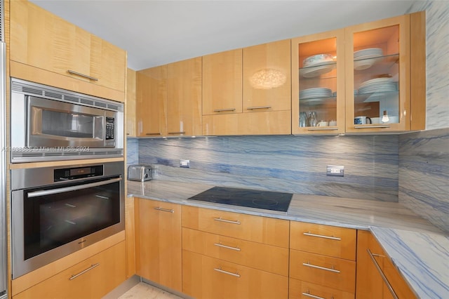 kitchen with decorative backsplash, appliances with stainless steel finishes, and light stone countertops