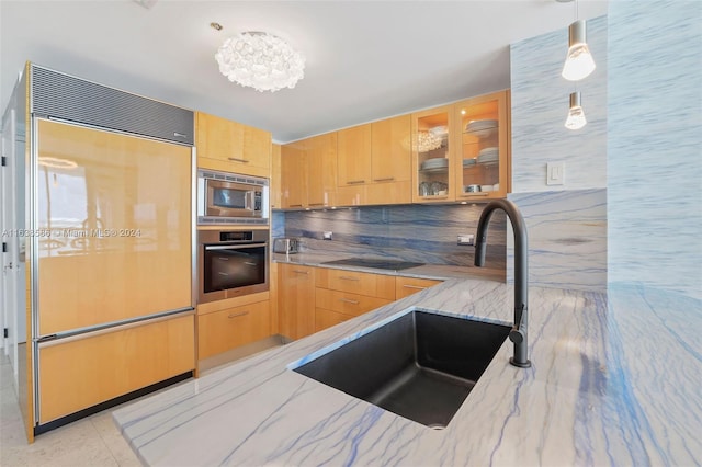 kitchen with light stone counters, light brown cabinetry, a sink, glass insert cabinets, and built in appliances