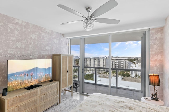 bedroom with wallpapered walls, a wall of windows, a view of city, and ceiling fan