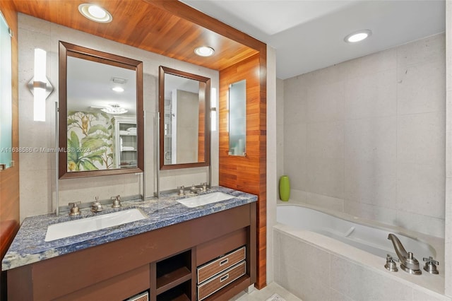 bathroom with double vanity, recessed lighting, a garden tub, and a sink