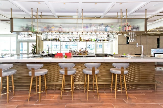 bar with a wealth of natural light, wood tiled floor, and a community bar