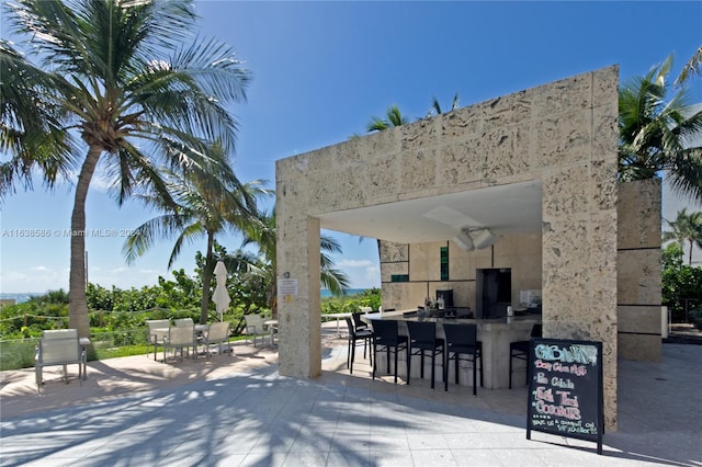 view of patio with ceiling fan and a bar