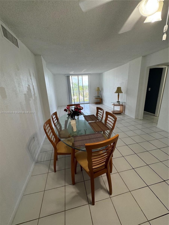 tiled dining space with a textured ceiling and ceiling fan