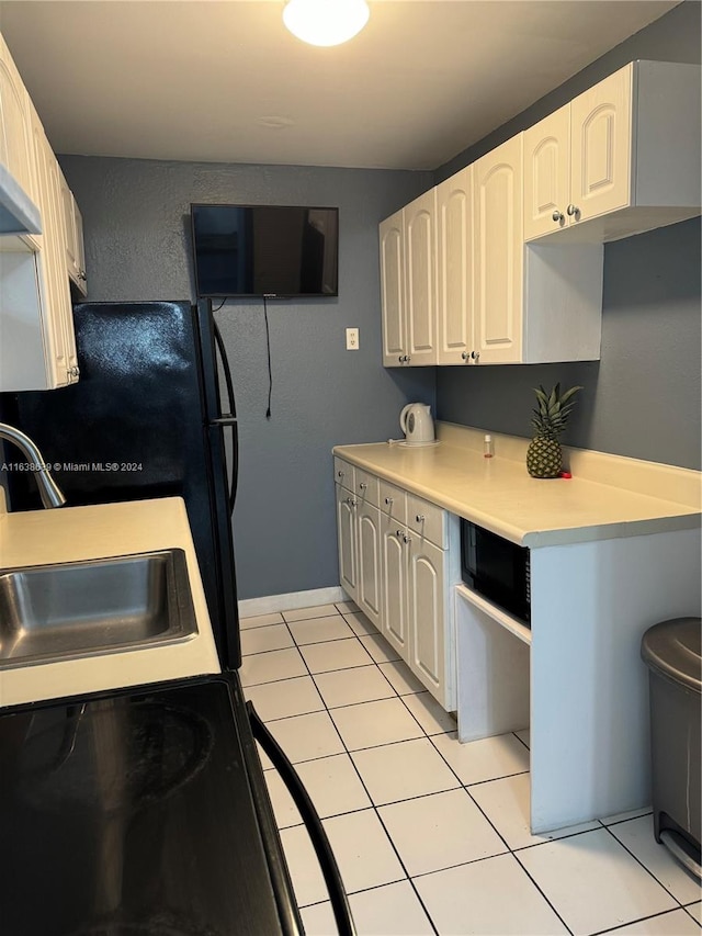 kitchen featuring sink, black microwave, white cabinetry, and light tile patterned floors