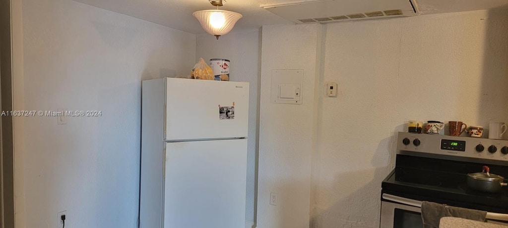 kitchen featuring electric range, white fridge, and electric panel