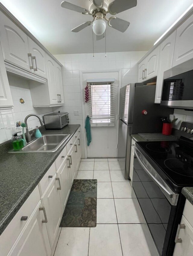 kitchen featuring stainless steel appliances, ceiling fan, light tile patterned flooring, backsplash, and white cabinetry