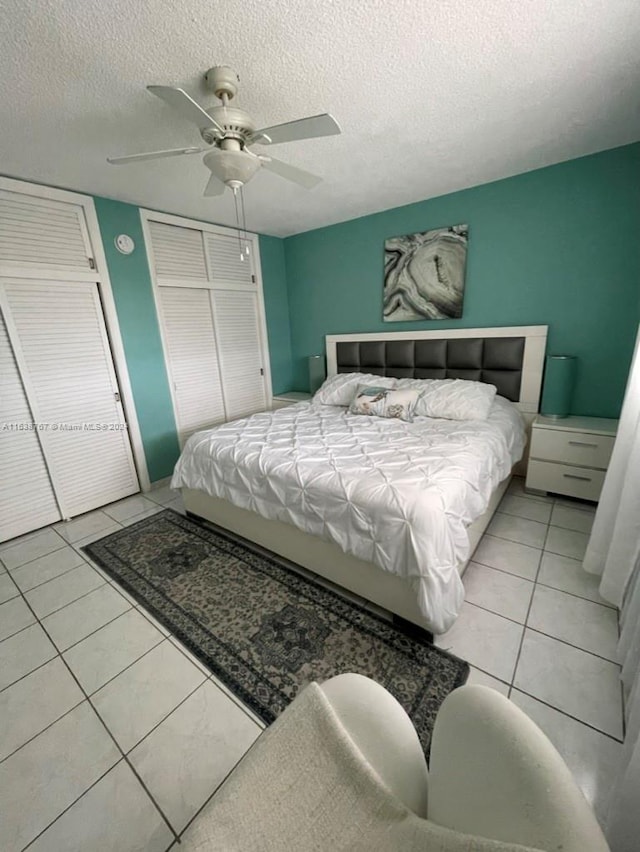 bedroom with a textured ceiling, light tile patterned floors, and ceiling fan