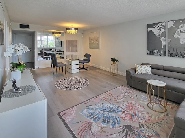 living room featuring hardwood / wood-style flooring, a notable chandelier, and a textured ceiling