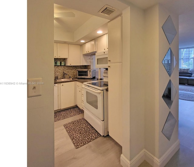 kitchen with sink, white appliances, light hardwood / wood-style floors, tasteful backsplash, and white cabinetry