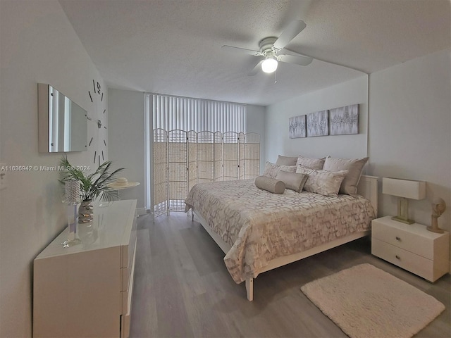 bedroom with ceiling fan, wood-type flooring, and a textured ceiling