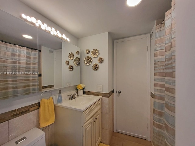 bathroom with tile walls, tile patterned flooring, vanity, and toilet