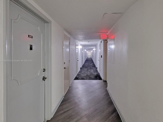 corridor featuring a textured ceiling and dark hardwood / wood-style floors