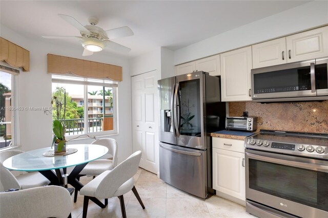 kitchen with appliances with stainless steel finishes, decorative backsplash, white cabinets, light tile patterned floors, and ceiling fan