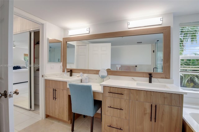 bathroom featuring a tub, double sink vanity, tile patterned floors, and a healthy amount of sunlight