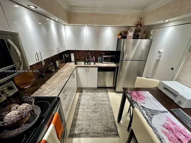 kitchen with sink, light tile patterned floors, light stone countertops, appliances with stainless steel finishes, and white cabinetry