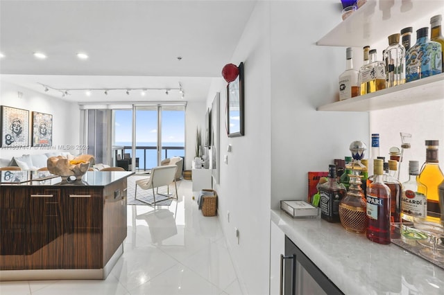 interior space featuring light tile patterned flooring, a water view, dark brown cabinetry, and rail lighting