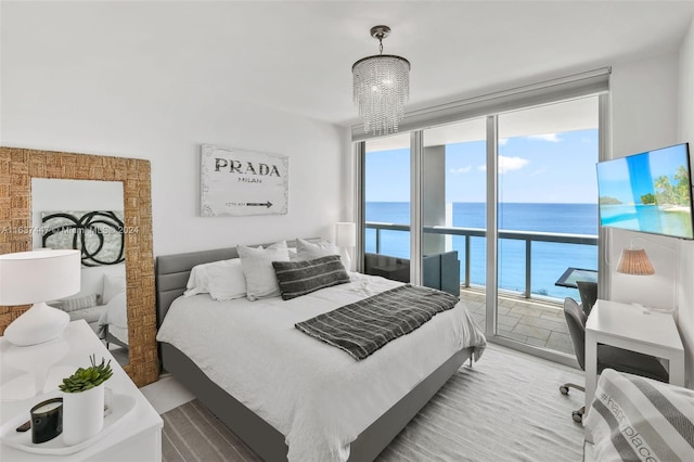 bedroom with access to exterior, a water view, a wall of windows, and an inviting chandelier