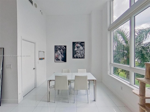 tiled dining room featuring a towering ceiling