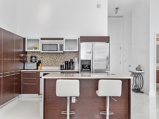 kitchen with light tile patterned floors, a breakfast bar area, stainless steel appliances, tasteful backsplash, and a kitchen island