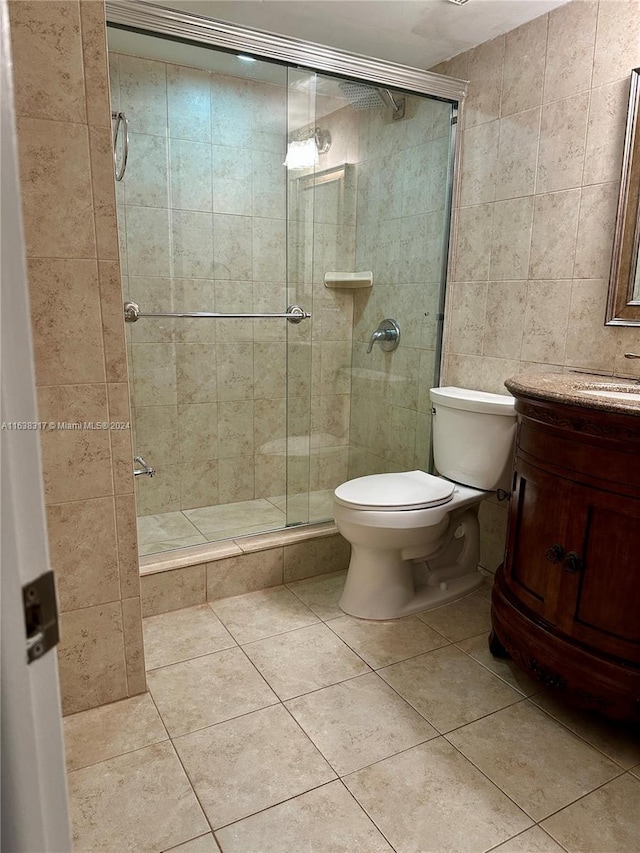 bathroom featuring tile walls, walk in shower, tile patterned floors, vanity, and toilet