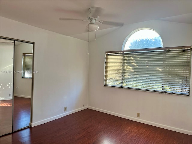 unfurnished bedroom with a closet, lofted ceiling, ceiling fan, and dark wood-type flooring